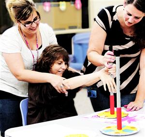 Photo of teachers helping a special education student work on an art project 